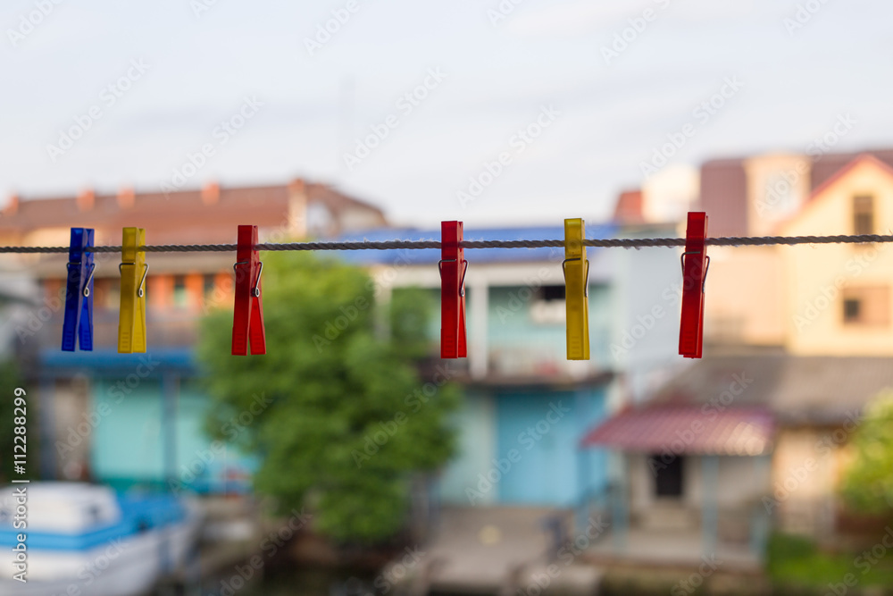 Colorful clothespins hanging in line at yellow house background