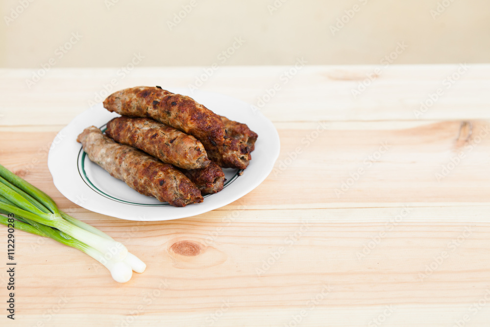 Lamb kebab on plate and onion on light wooden background with copyspace. Cuisine background. Eastern food. Street food. Hot grilled kebab. Weekend barbeque.