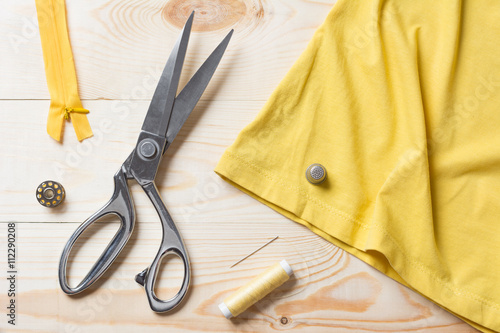 Cutting yellow fabric with a taylor scissors on wooden table