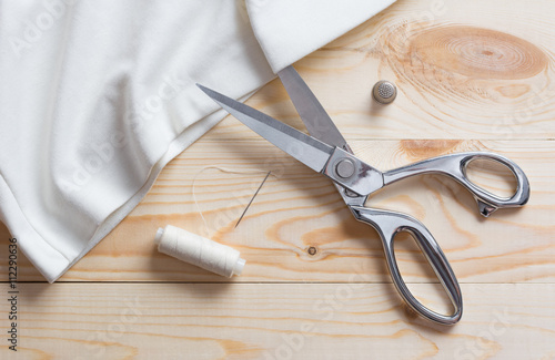 Cutting white fabric with a taylor scissors on wooden table photo