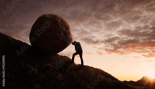 Photo Young businessman pushing large stone uphill