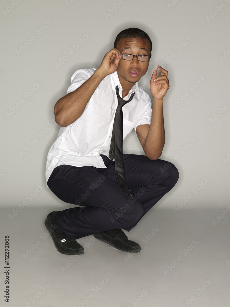 view of a businessman crouching and adjusting spectacles. view of a businessman crouching and adjusting spectacles.