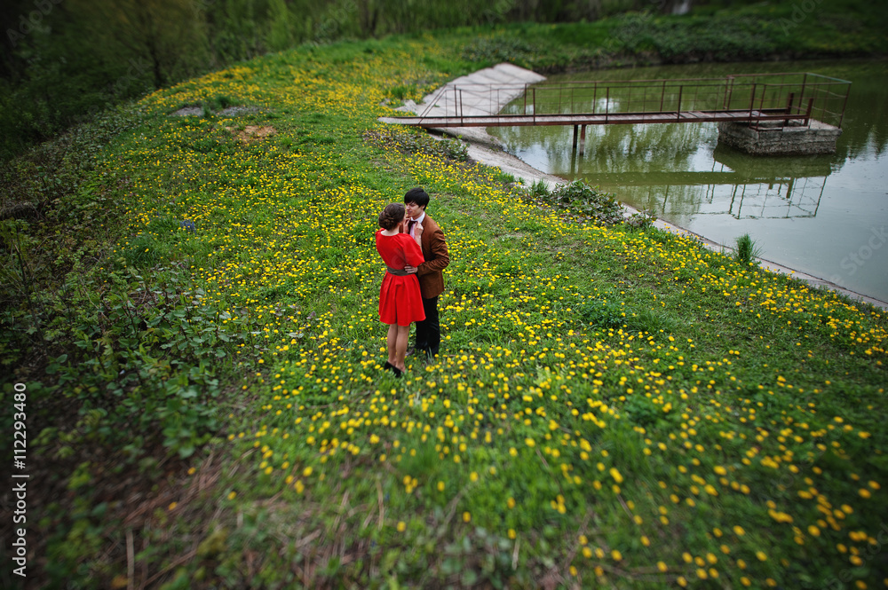 Couple hugging in love at yellow flowers field near lake and pon