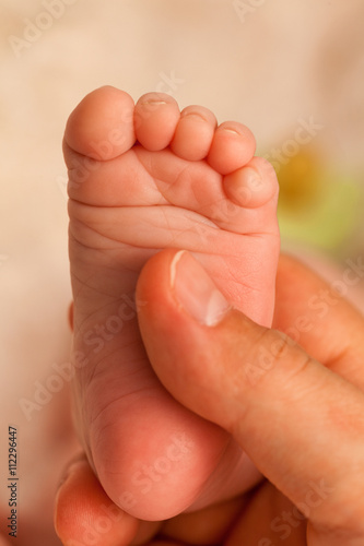Foot of one week old baby in father  s hand. Close up  vertical shot