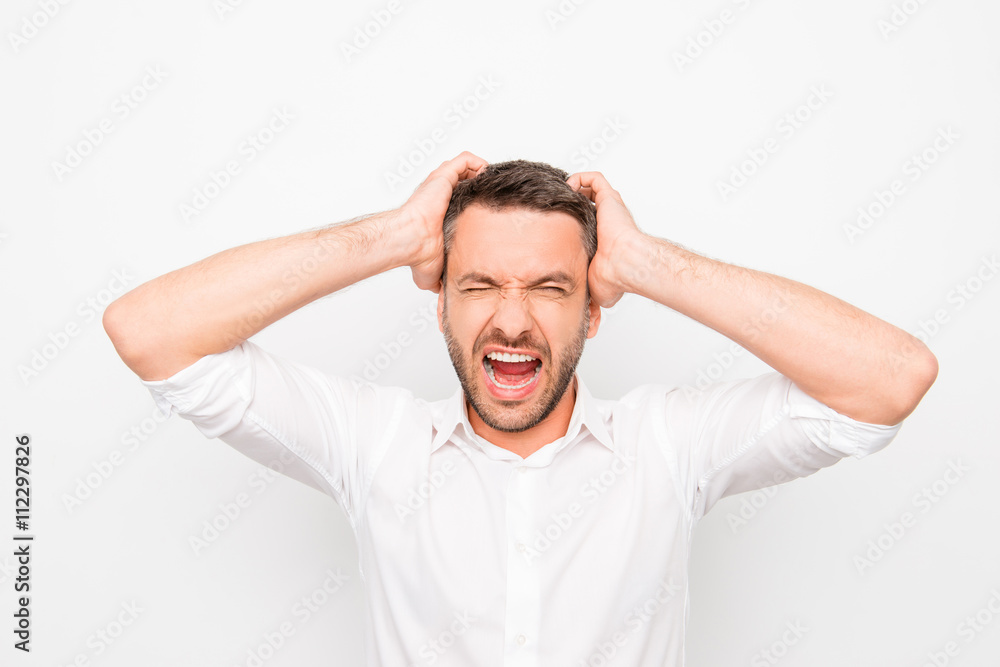 Handsome depressed young man holding his head and screaming Handsome depressed young man holding his head and screaming