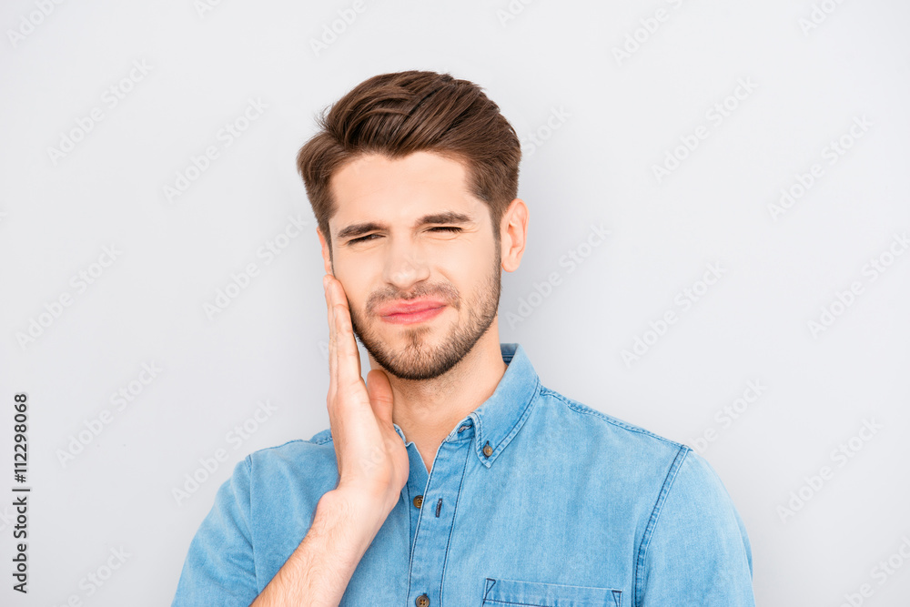 Depressed ill man having toothache and touching cheek Depressed ill man having toothache and touching cheek