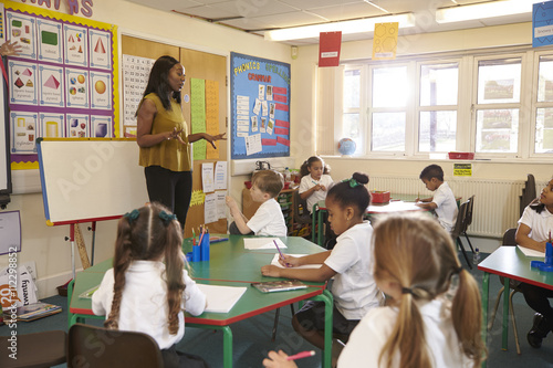Pupils Working At Desks In Elementary School Classroom