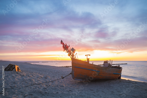 Zachód słońca nad morską plażą,kutry rybackie na piasku
