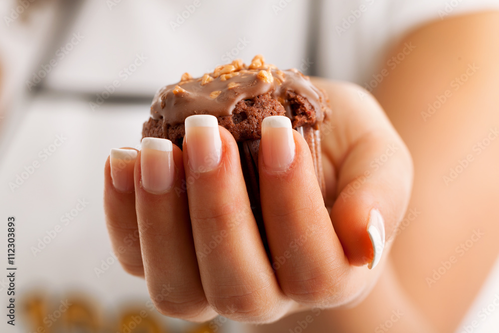 One chocolate muffin in hand of a female, close up One chocolate muffin in hand of a female, close up
