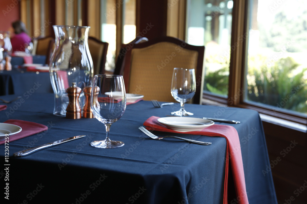 Table setting in a restaurant with a blue tablecloth and red na Table setting in a restaurant with a blue tablecloth and red na