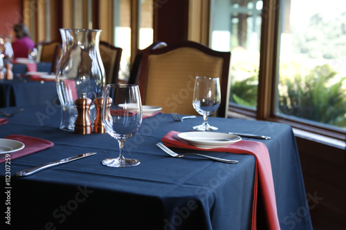 Table setting in  a restaurant with a blue tablecloth and red na