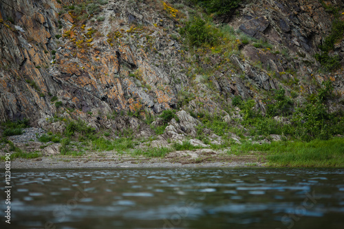 Rocks with orange lichen, scenic view from river