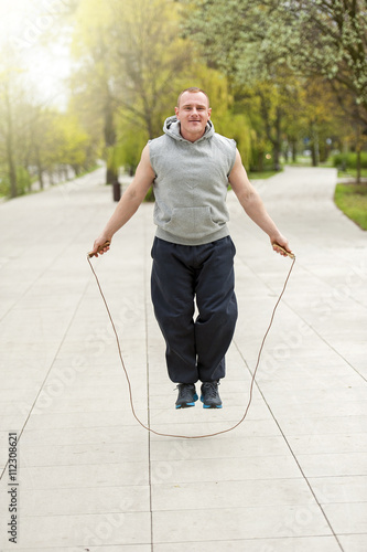 Man with jump rope in park.