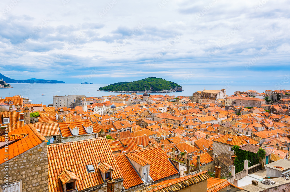 Orange roofs of buildings in old town Dubrovnik and island Lokrum on background, Croatia