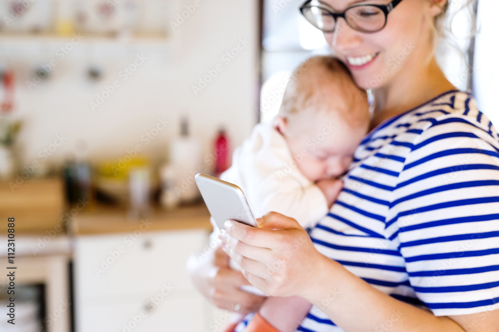 Mother holding little baby looking at cell phone Mother holding little baby looking at cell phone