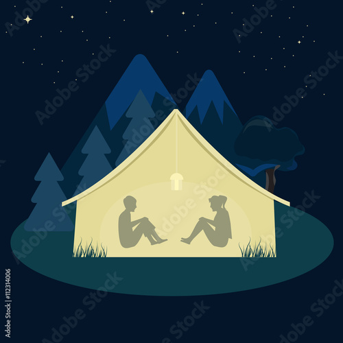 Two young man and woman camping in tent at night.