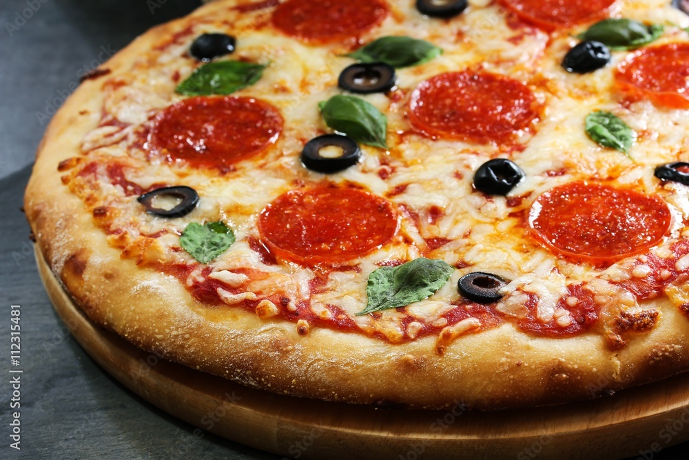 Homemade Pizza with basil black olives and peperoni, close up, selective focus Homemade Pizza with basil black olives and peperoni, close up, selective focus