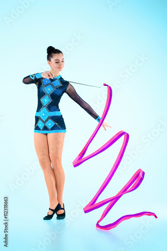 The girl doing gymnastics dance with colored ribbon on a blue background