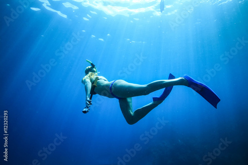 Underwater woman snorkeling in blue tropical sea