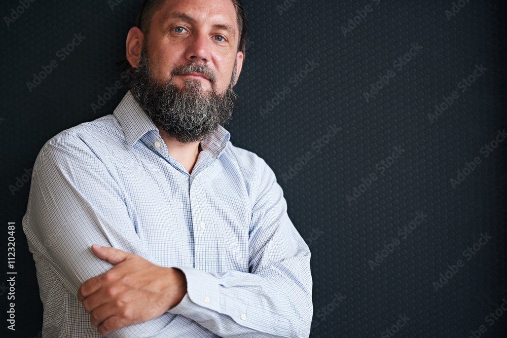 Rugged looking mature man with beard against black textured background Rugged looking mature man with beard against black textured background