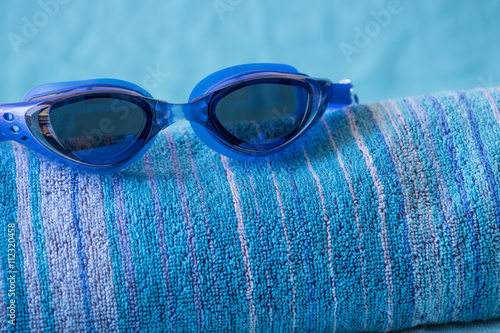 Blue swimming goggles on beach towel