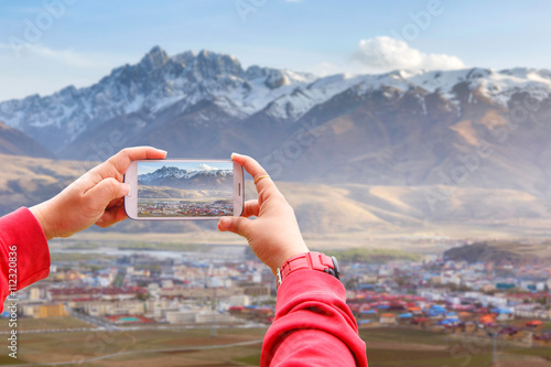 Smartphone photographing Village inclose mountain a famous landmark in Ganzi, Sichuan, China. photo