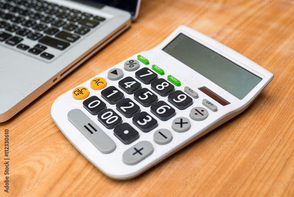 Calculator with laptop on wooden background Calculator with laptop on wooden background