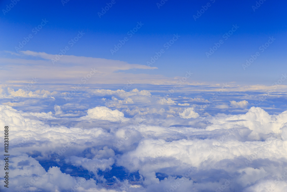 Big white clouds at blue sky view from the airplane seat