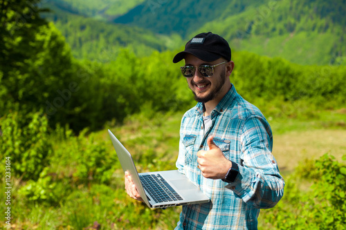 male model working in the mountains on a laptop © ponomarencko