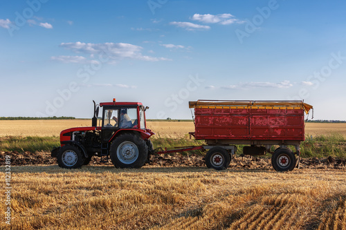 Red tractor with red trailer ina field