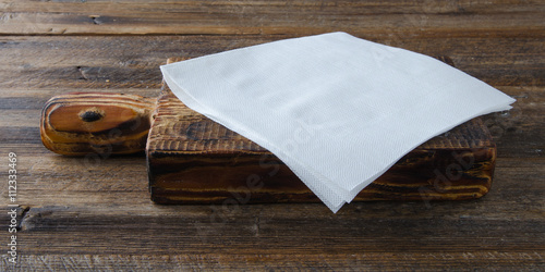 white paper napkin at cutting board on old wooden table