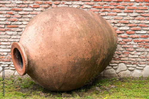 Jug for wine-making on brick wall background. photo