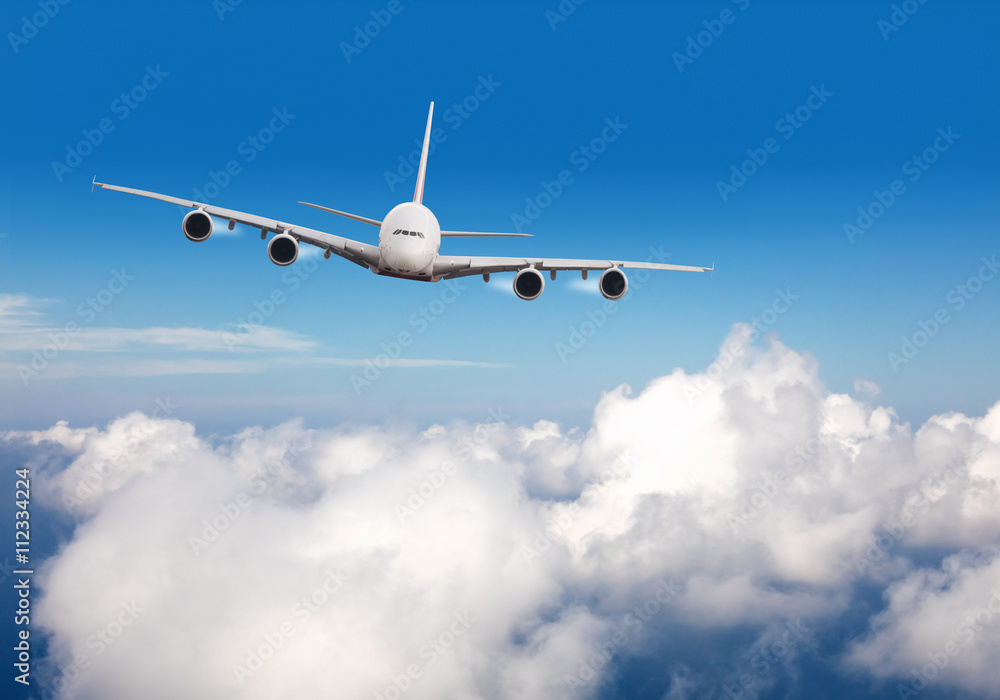 Obraz premium Komercyjny samolot odrzutowy lecący nad chmurami
