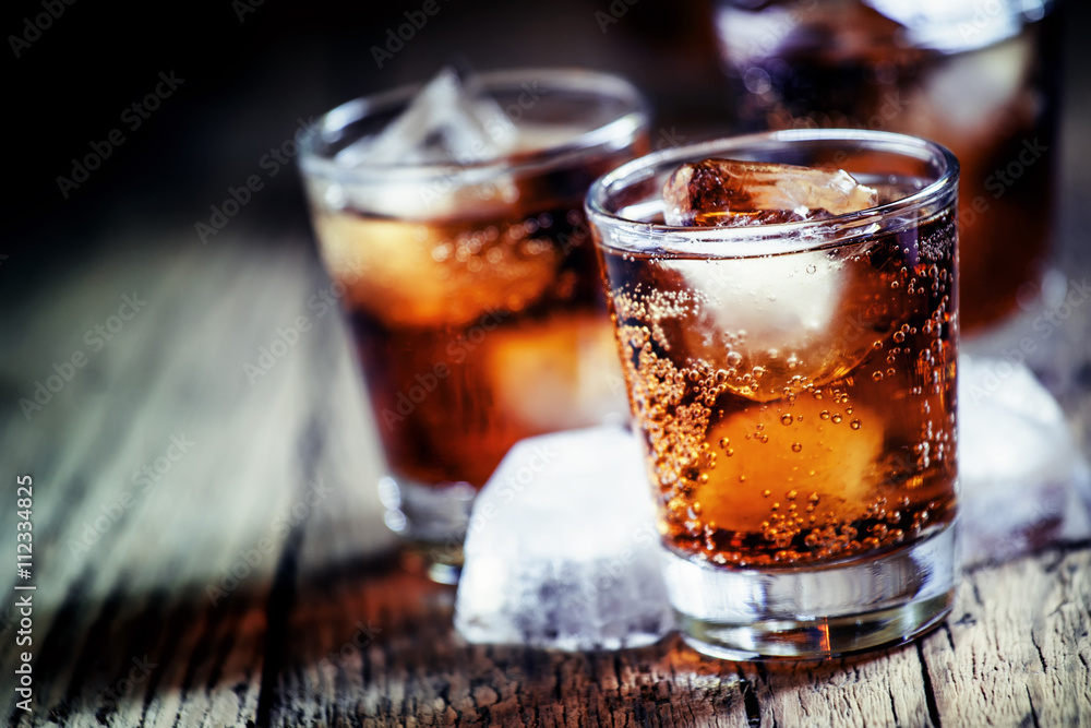 Rum and cola and ice, dark wood background, selective focus, sha Rum and cola and ice, dark wood background, selective focus, sha