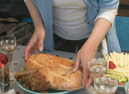 Woman hands are setting loaf on serving plate for lunch.