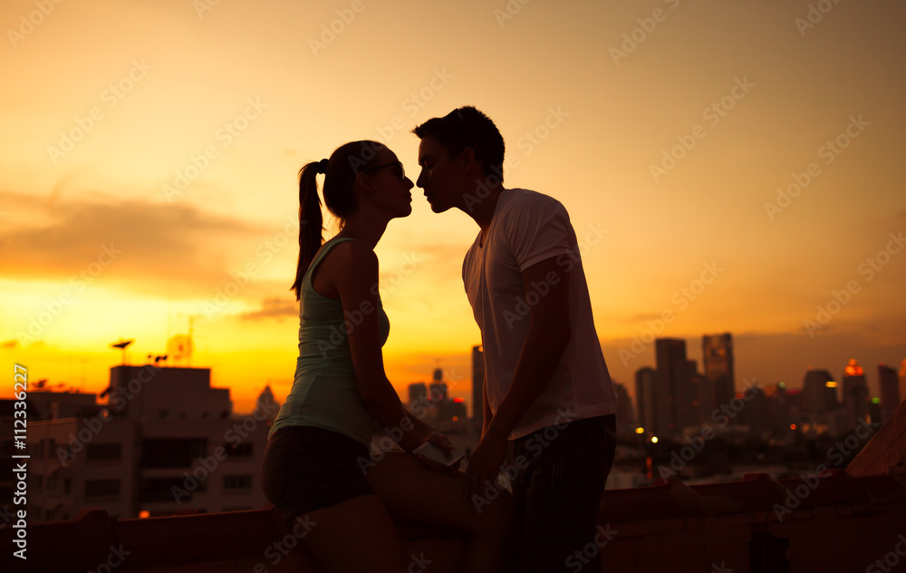 Couple kissing  in the city at sunset.

