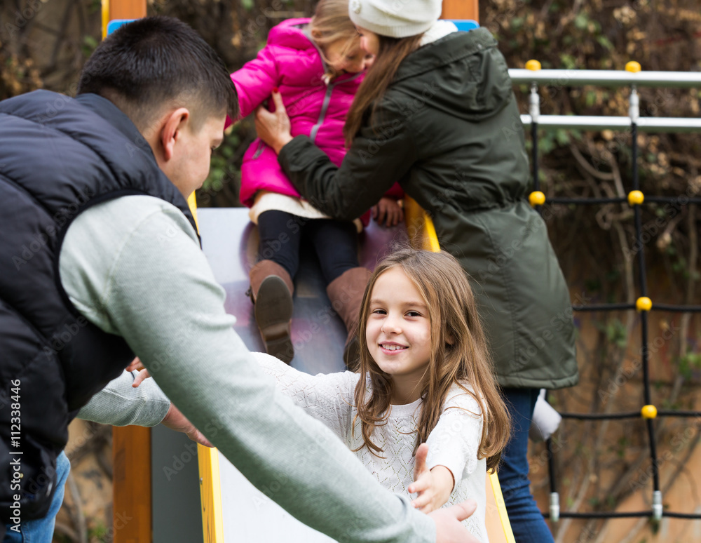 Parents helping kids on slide