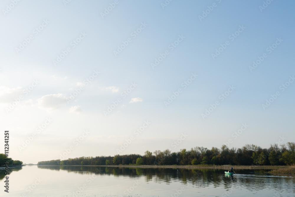 Fisherman floating on a boat on the river on a summer day