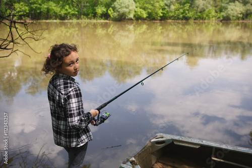eight year old girl in a plaid shirt catches fish in the river summer in the village