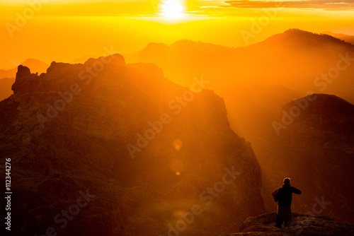 Man playing accordion on mountain landscape at sunset