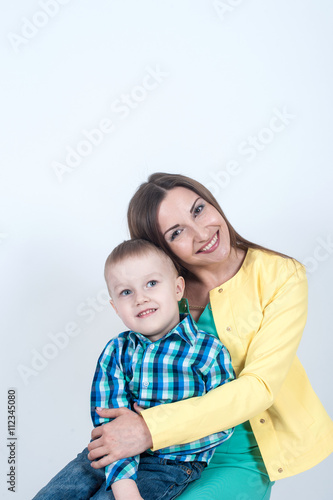Boy in shirt sitting with mom on light background