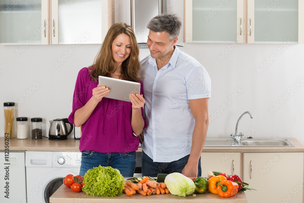 Couple Looking At Recipe On Digital Tablet Couple Looking At Recipe On Digital Tablet