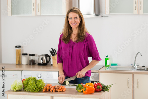 Woman Cutting Vegetable In Kitchen