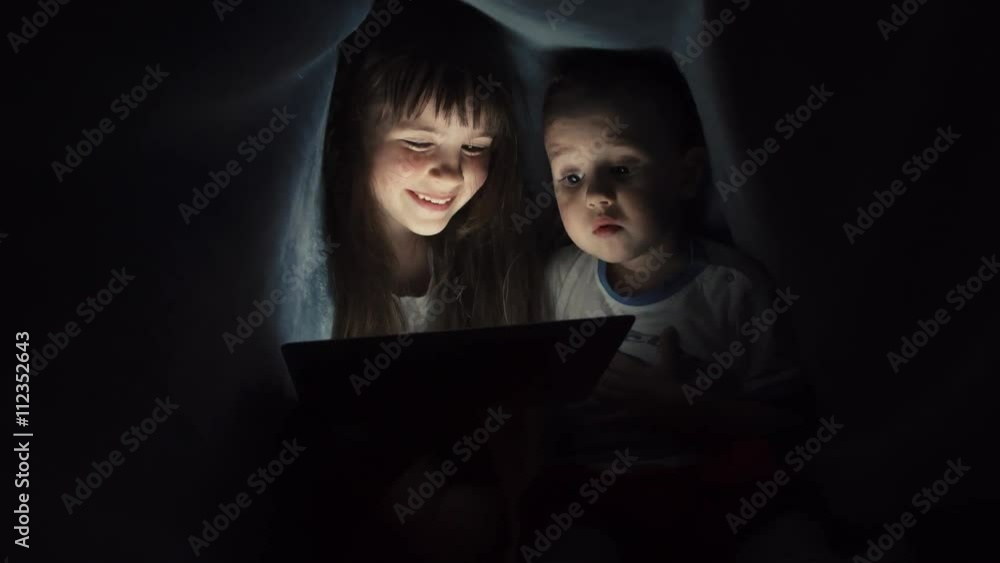 Girl and boy reading book under blanket Girl and boy reading book under blanket