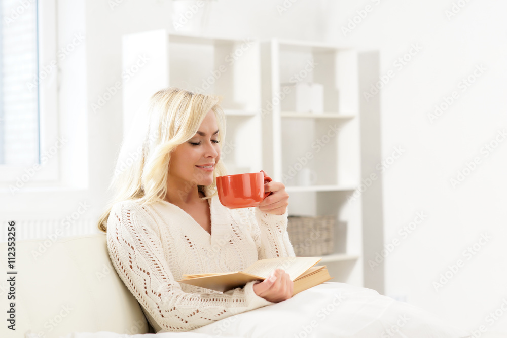 Beautiful smiling happy woman reading a book and having a cup of Beautiful smiling happy woman reading a book and having a cup of