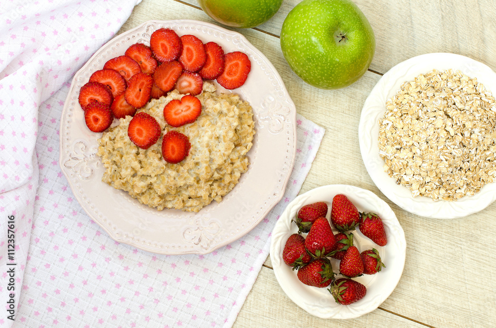 Oatmeal with strawberries and apples on the table. The view from Oatmeal with strawberries and apples on the table. The view from