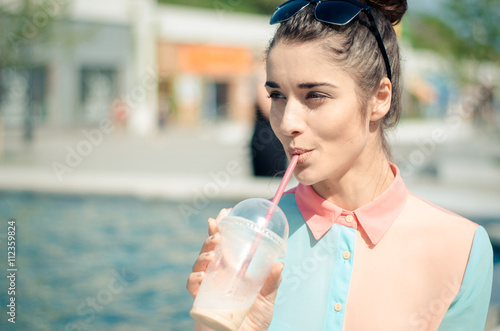 pretty smiling girl with iced latte in sunny city