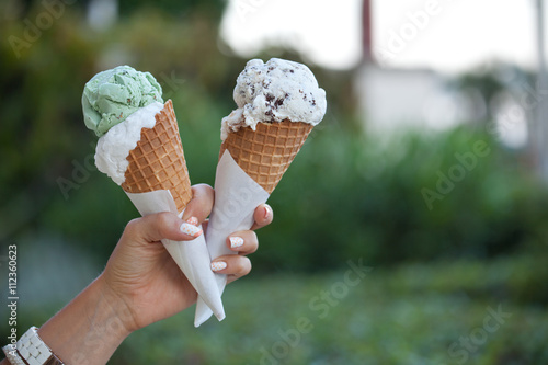 Fototapeta Two colorful tasty ice cream cones in hand.