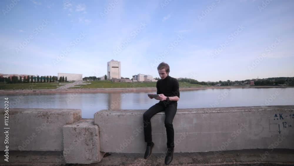 Young man getting message with tablet computer near the city lake. HD. Young man getting message with tablet computer near the city lake. HD.
