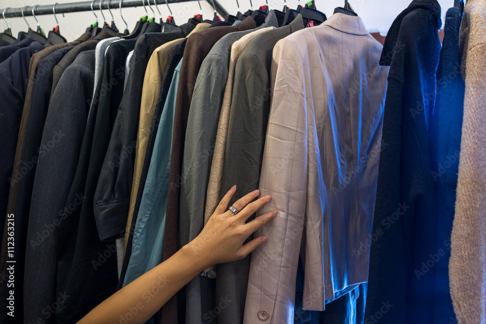 Female hand on male jackets on rack Female hand on male jackets on rack